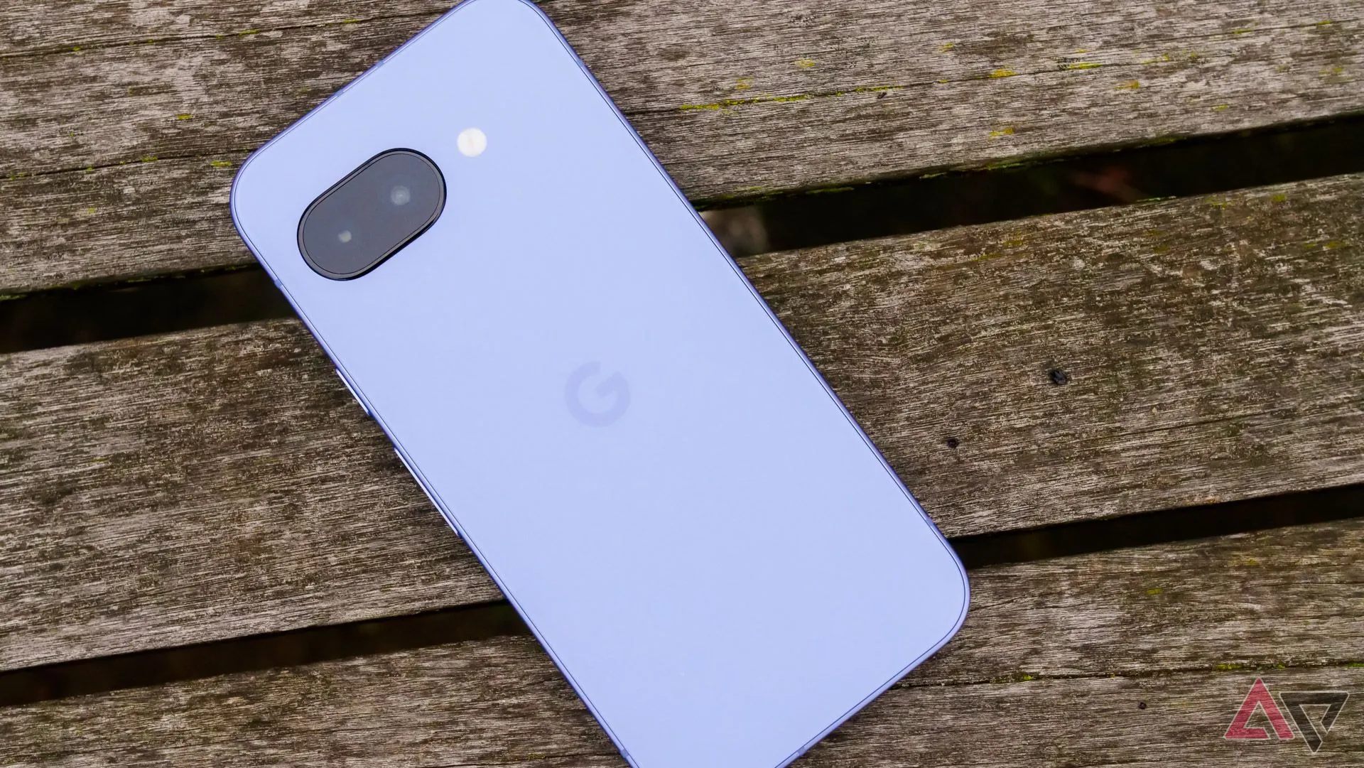 Điện thoại Google Pixel 9a đặt úp mặt xuống trên ghế gỗ trong công viên