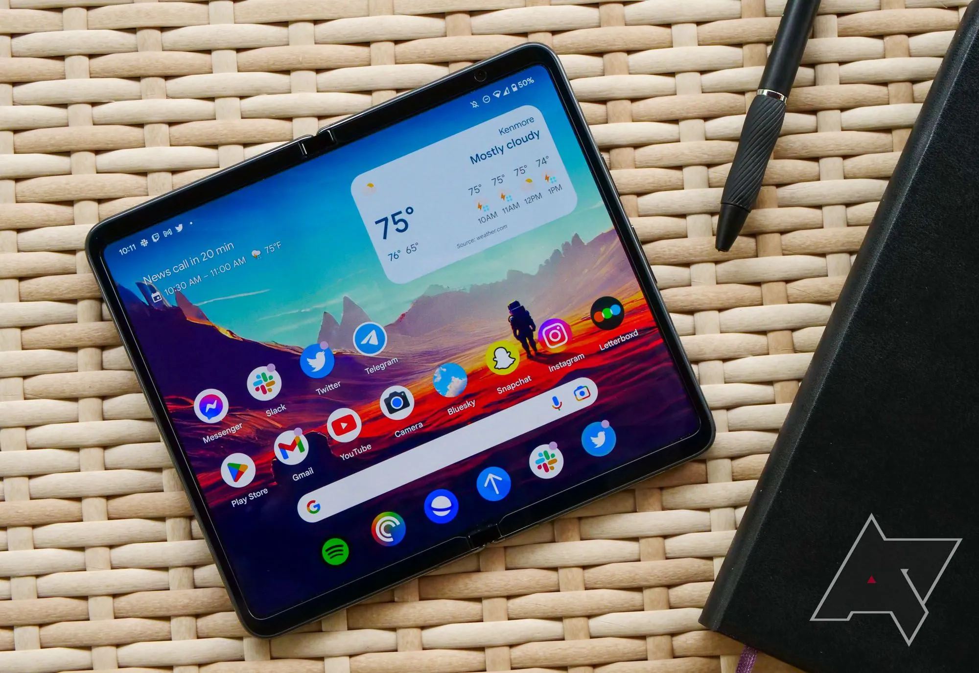 Google Pixel Fold đặt trên bàn gỗ cùng sổ và bút