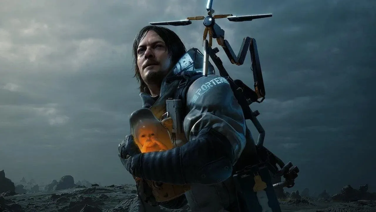 Bìa game Death Stranding với hình ảnh người đàn ông ôm em bé trong bộ phận bảo vệ đầy nước