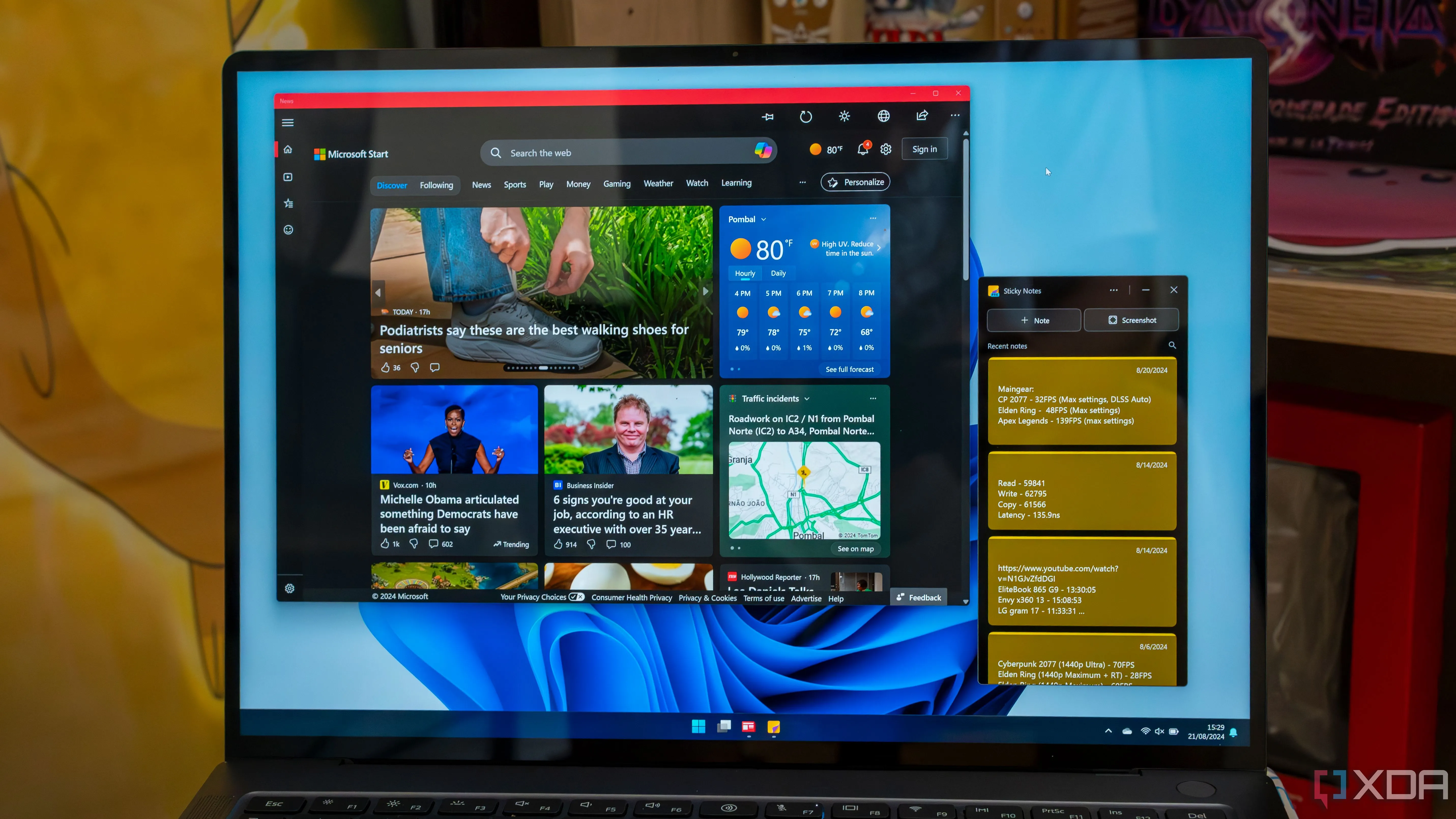 Một chiếc laptop Windows 11 đang chạy các ứng dụng như Microsoft News và Sticky Notes.