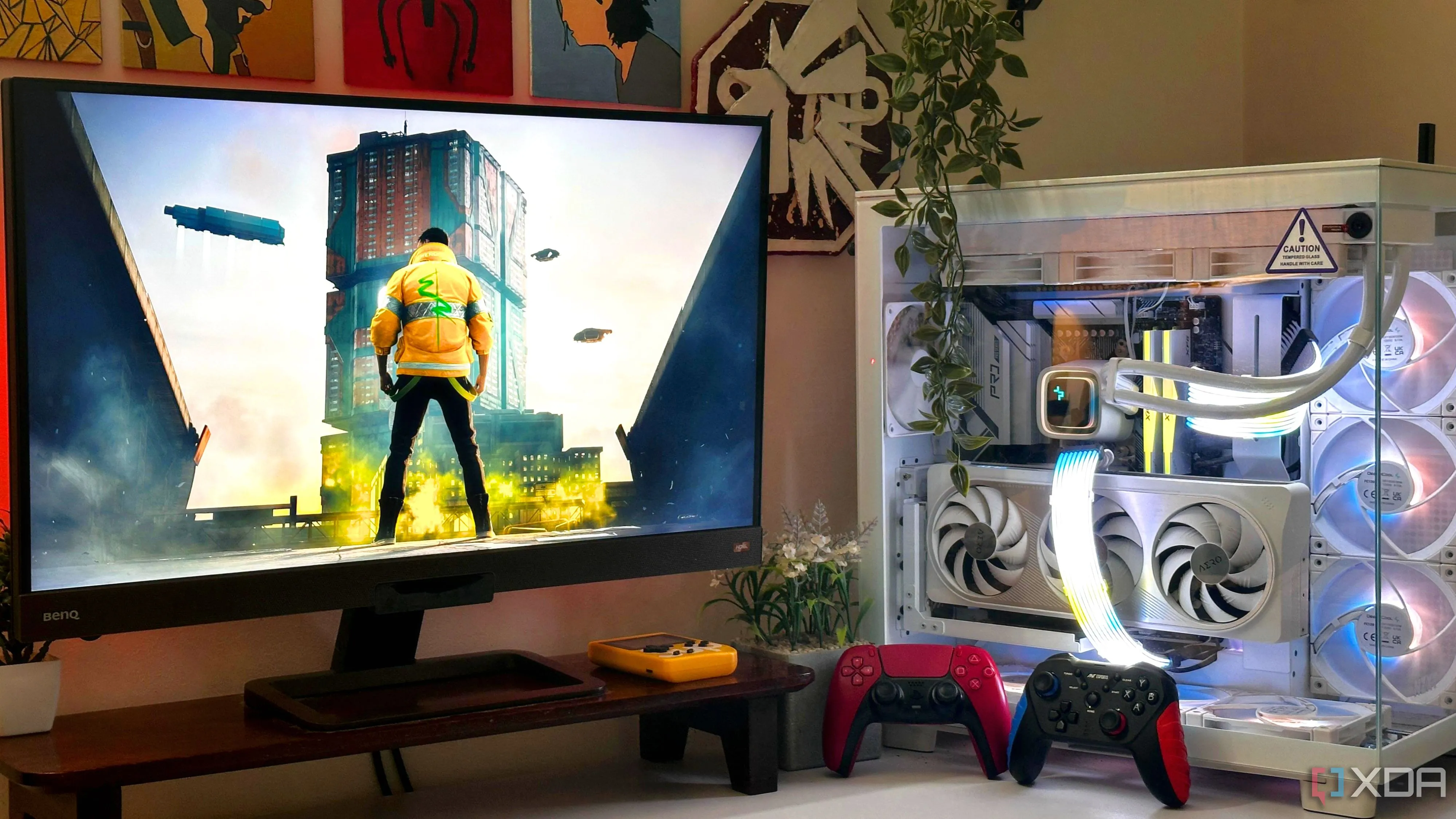 Một góc chơi game với màn hình hiển thị tựa game Cyberpunk 2077 và tay cầm đặt cạnh thùng máy tính.
