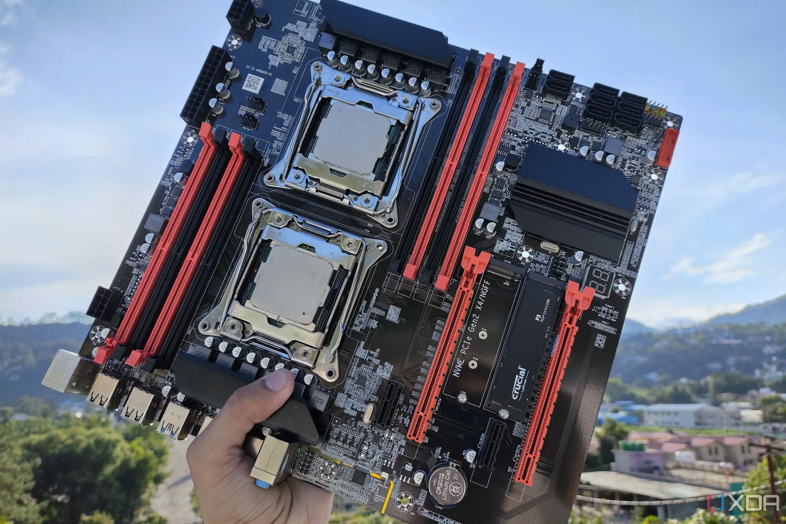 Một người đang cầm bo mạch chủ server X99 dual-CPU, tập trung vào khu vực VRM và chipset.
