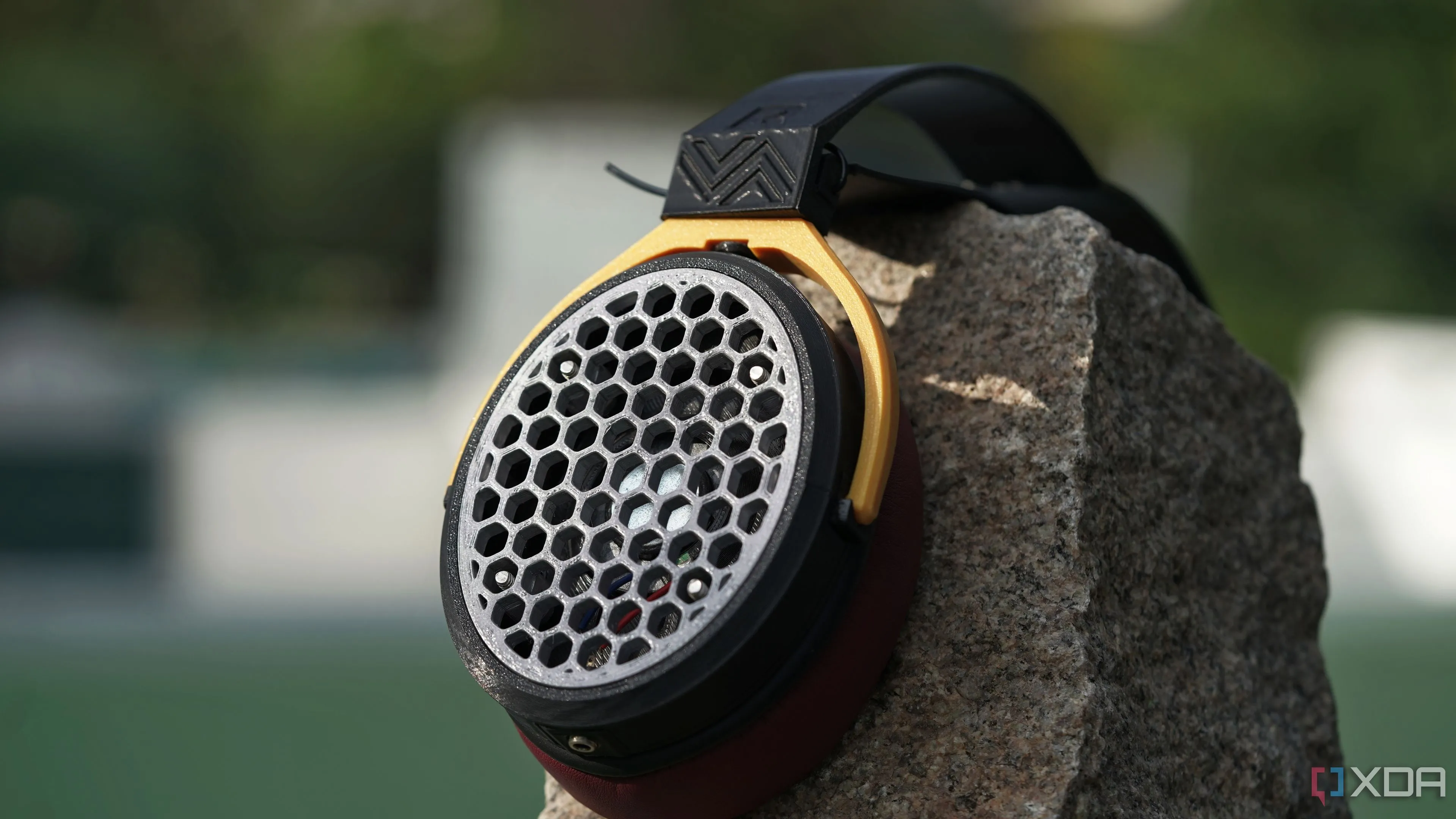 Tai nghe in 3D kiểu open-back đặt trên tảng đá, một bên earcup lộ rõ