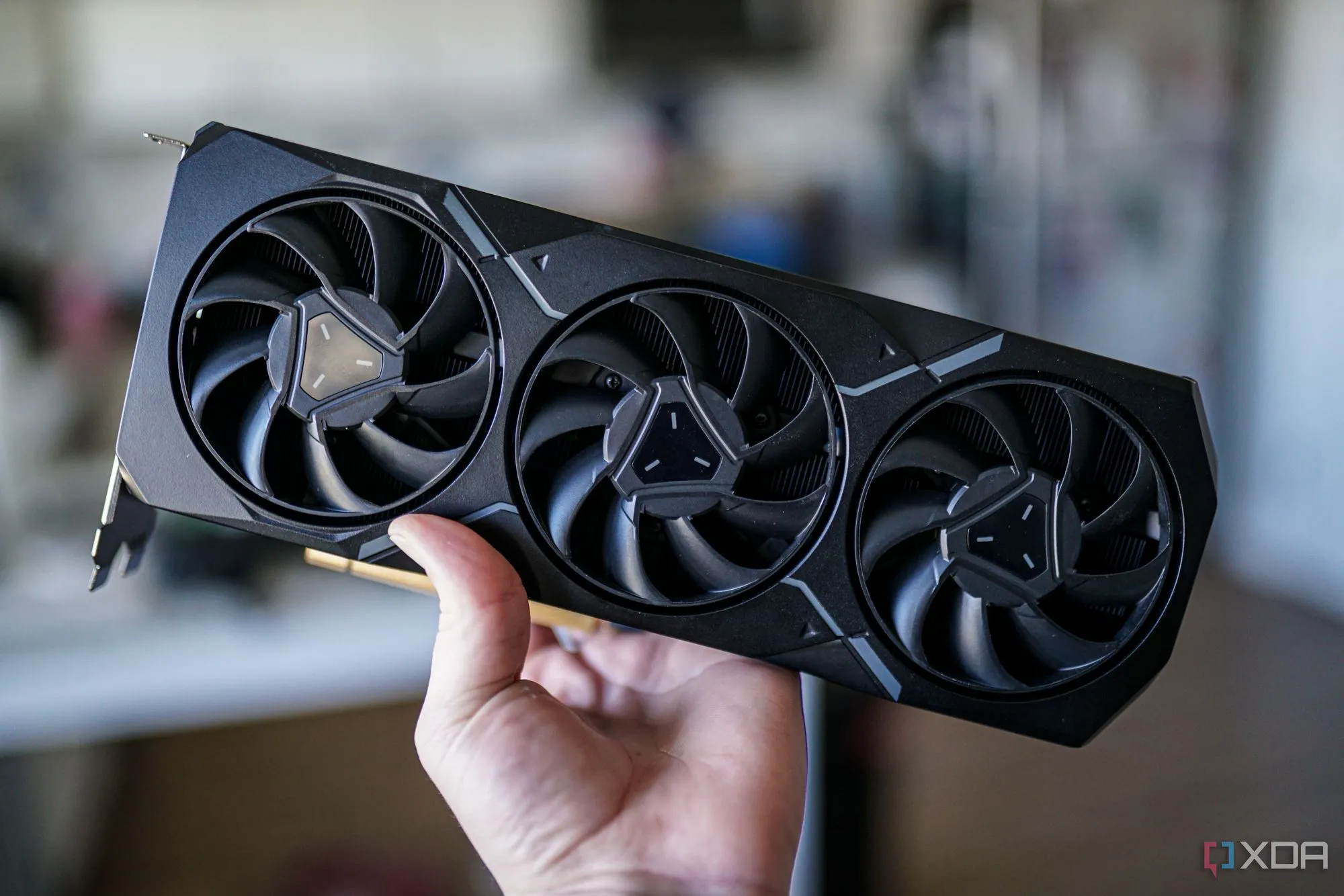 Bàn tay cầm card đồ họa AMD Radeon RX 7900 XT, tượng trưng cho sự cạnh tranh từ AMD trên thị trường GPU