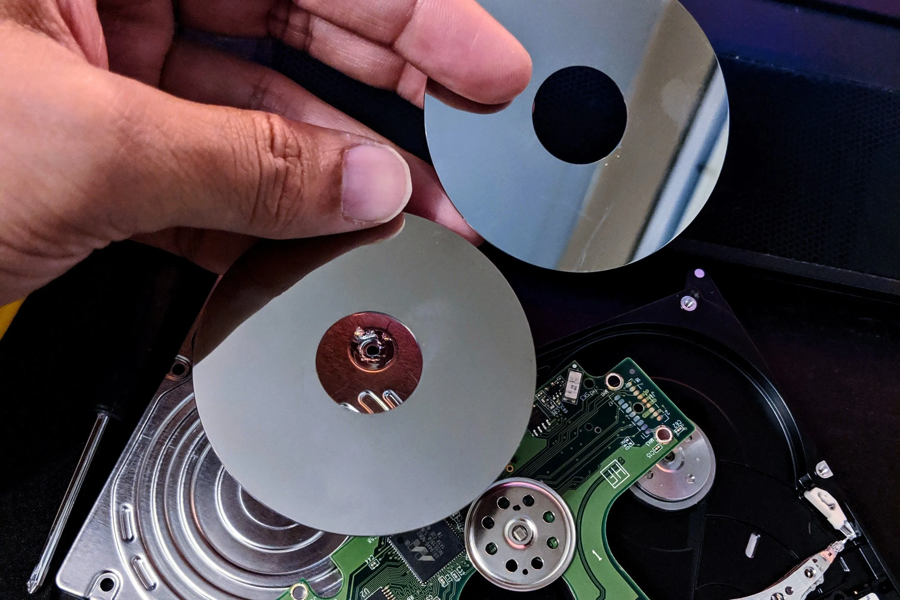 Các đĩa từ (platter) của một ổ cứng cơ học (HDD) được tháo rời, minh họa các bộ phận dễ tổn thương do va đập, nhấn mạnh sự mong manh của HDD so với SSD.