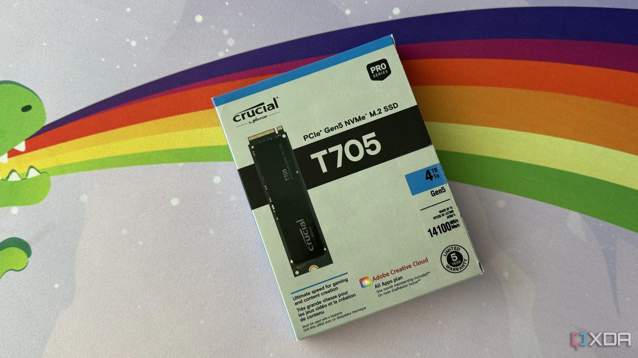 Hộp ổ cứng SSD Crucial T705 PCIe Gen5 đặt trên tấm lót bàn màu cầu vồng, minh họa sự phát triển của công nghệ lưu trữ SSD.