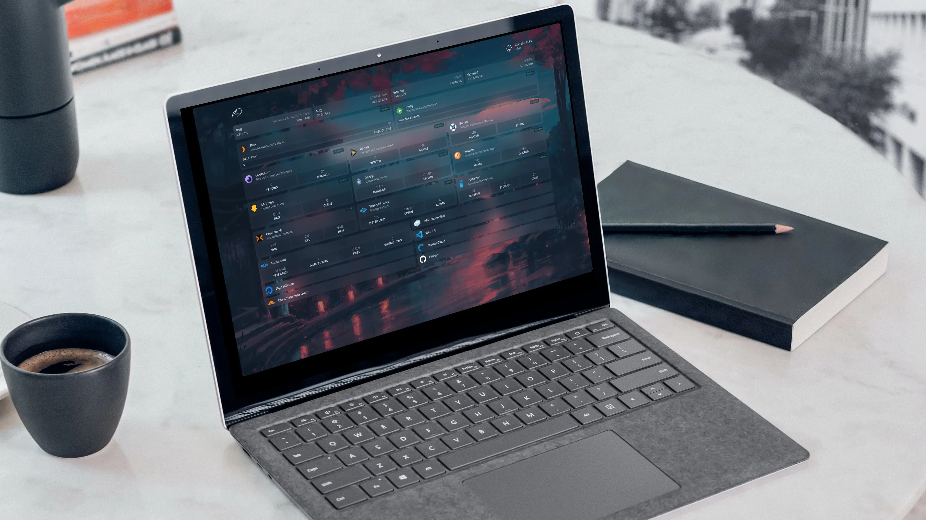 Laptop với màn hình dashboard Homarr, bên cạnh tách cà phê và sổ tay