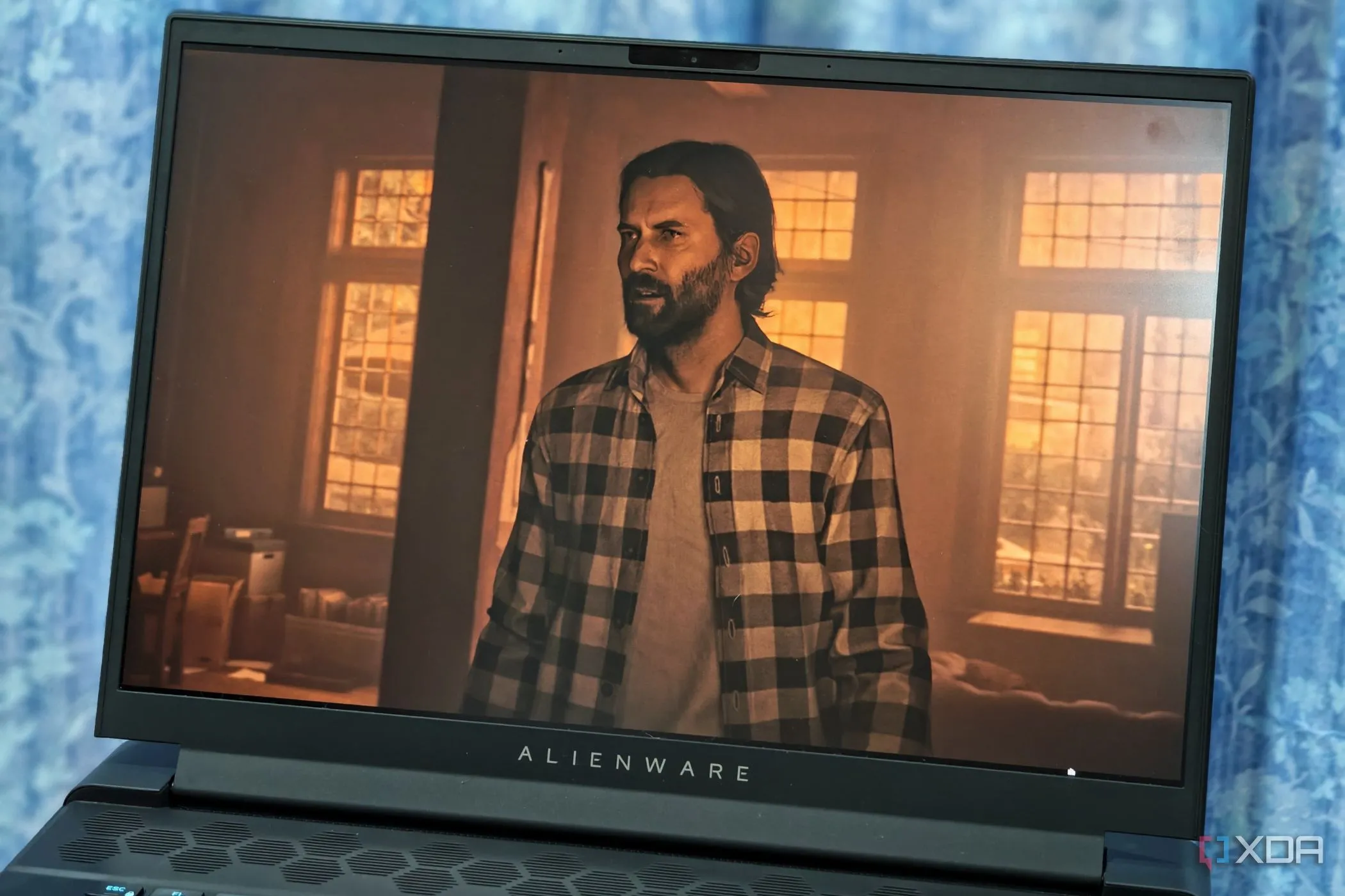 Màn hình laptop Alienware m16 hiển thị cảnh chơi game Alan Wake 2 với đồ họa chất lượng cao