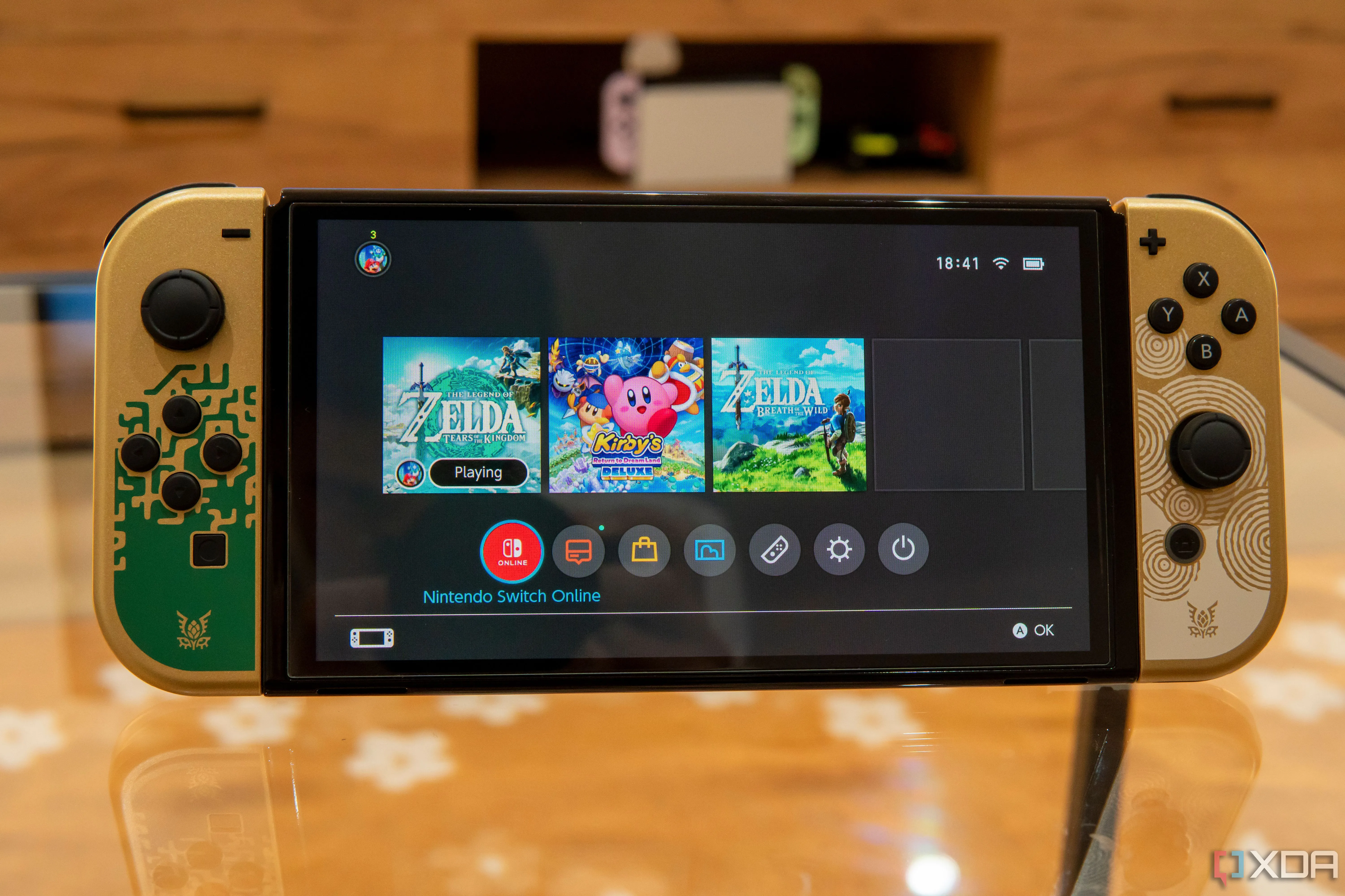 Màn hình Nintendo Switch OLED hiển thị giao diện Home với một game đang chạy nền