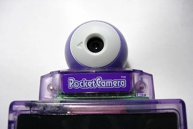Máy ảnh Nintendo Pocket Camera được gắn trên một chiếc Game Boy màu tím đang hiển thị một bức ảnh chụp màn hình đơn sắc