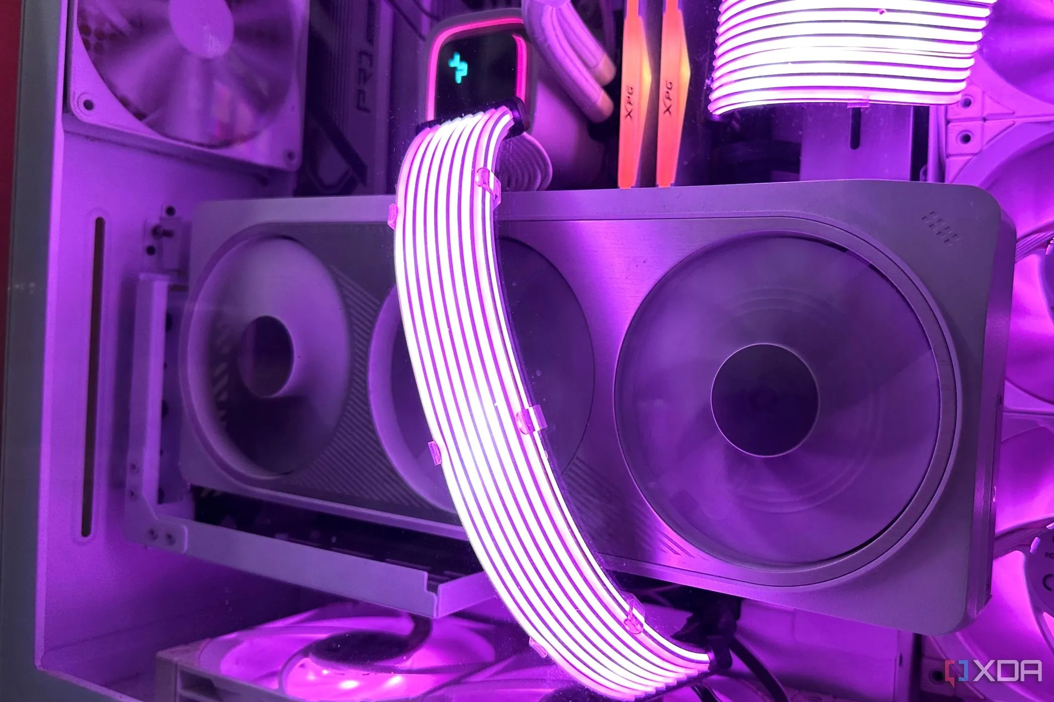 Một chiếc card đồ họa Nvidia RTX 4070 Ti màu trắng với cáp Lian Li Strimer tím chạy qua, đặt trong vỏ máy tính trắng.