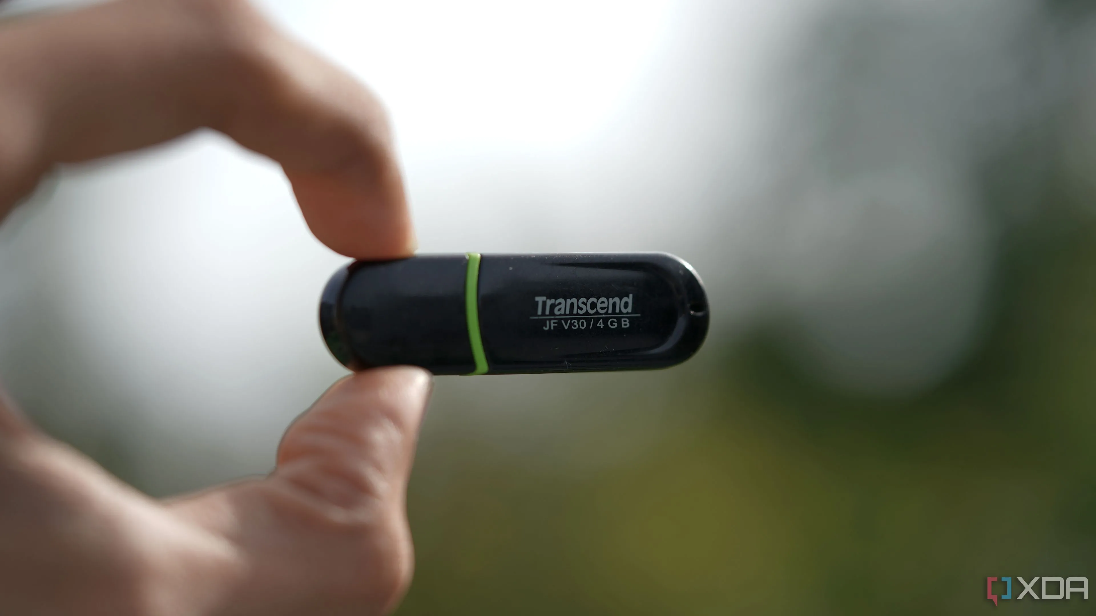 Một chiếc USB Transcend 4GB nhỏ gọn được giữ trong tay, biểu tượng cho dung lượng và tốc độ hạn chế của USB cũ