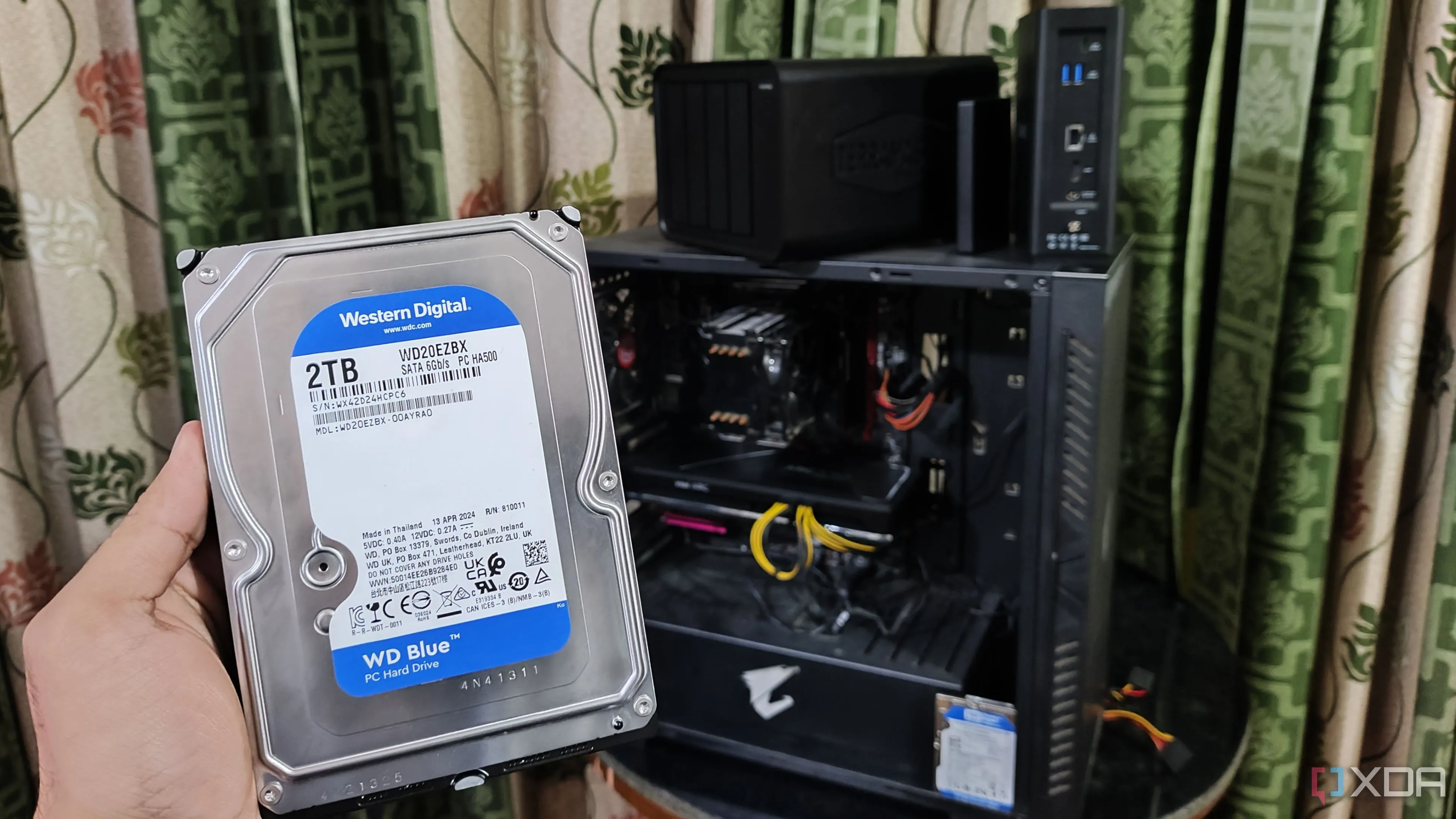 người giữ ổ cứng trước máy tính và hai thiết bị NAS TerraMaster