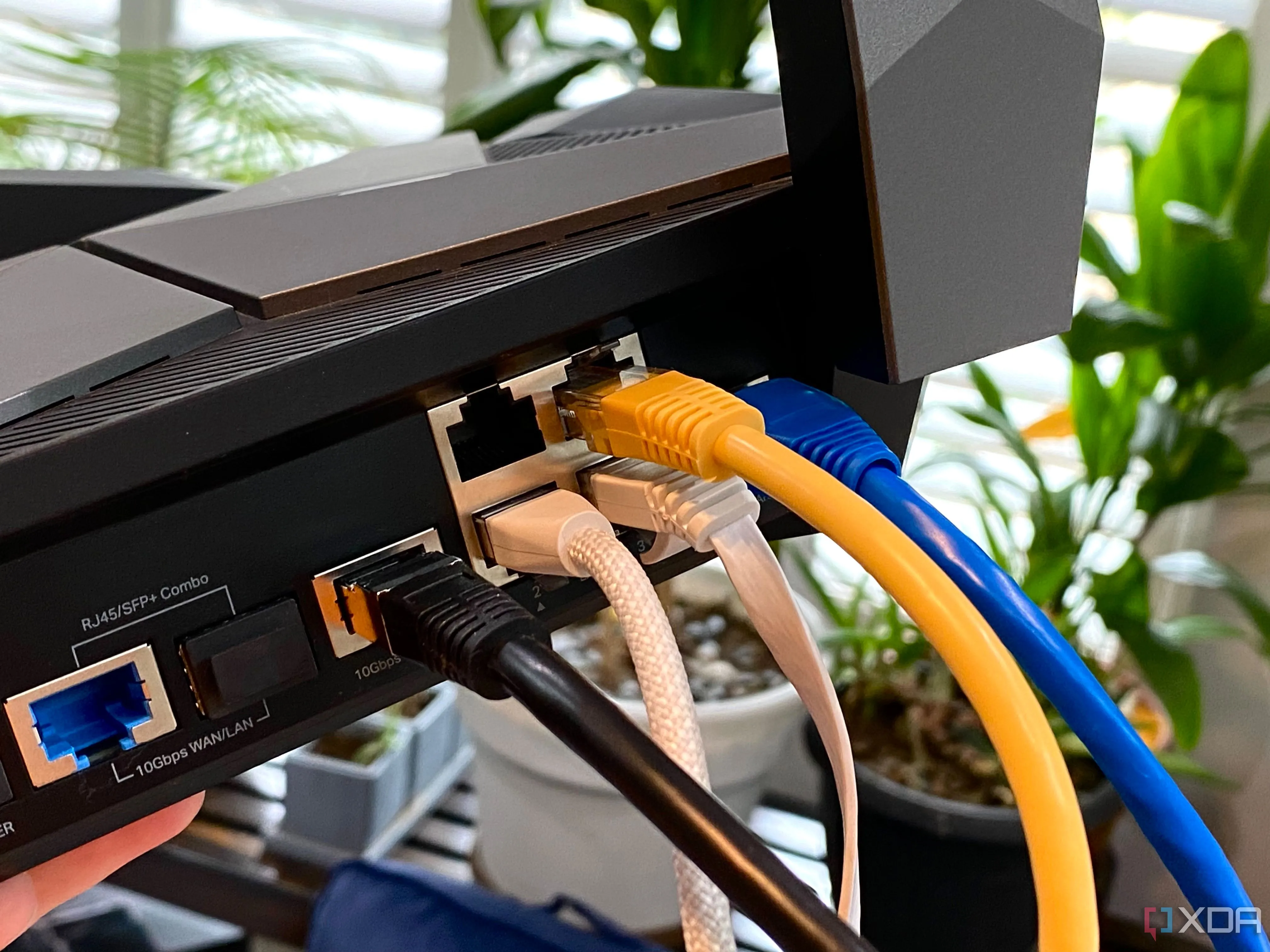 Nhiều loại cáp Ethernet màu sắc khác nhau được cắm vào bộ định tuyến TP-Link Archer AXE300, thể hiện kết nối mạng đa dạng và quản lý cáp