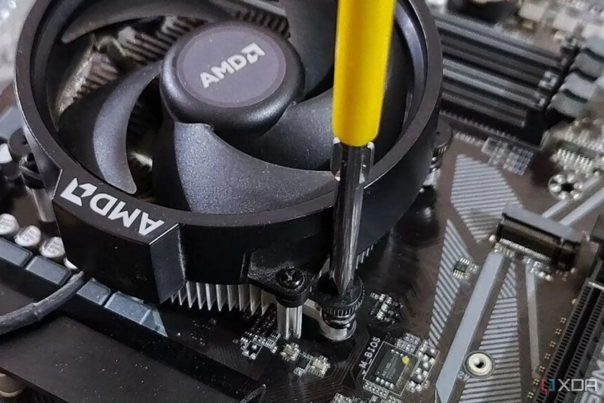 Tản nhiệt stock của AMD đang được lắp vào bo mạch chủ bằng tua vít