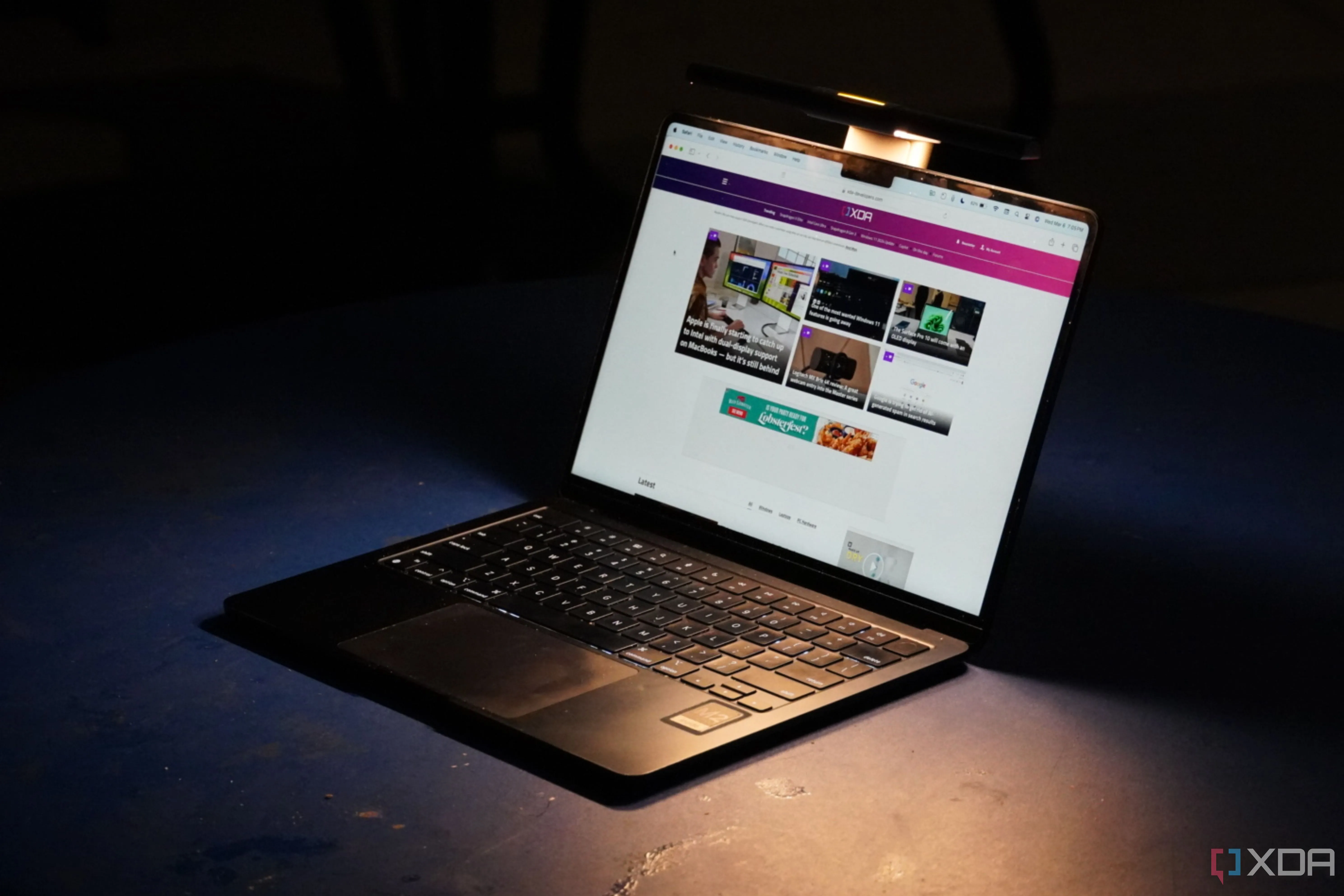 Thanh đèn BenQ LaptopBar gắn trên MacBook Air trong môi trường tối, gợi ý về ánh sáng hỗ trợ.
