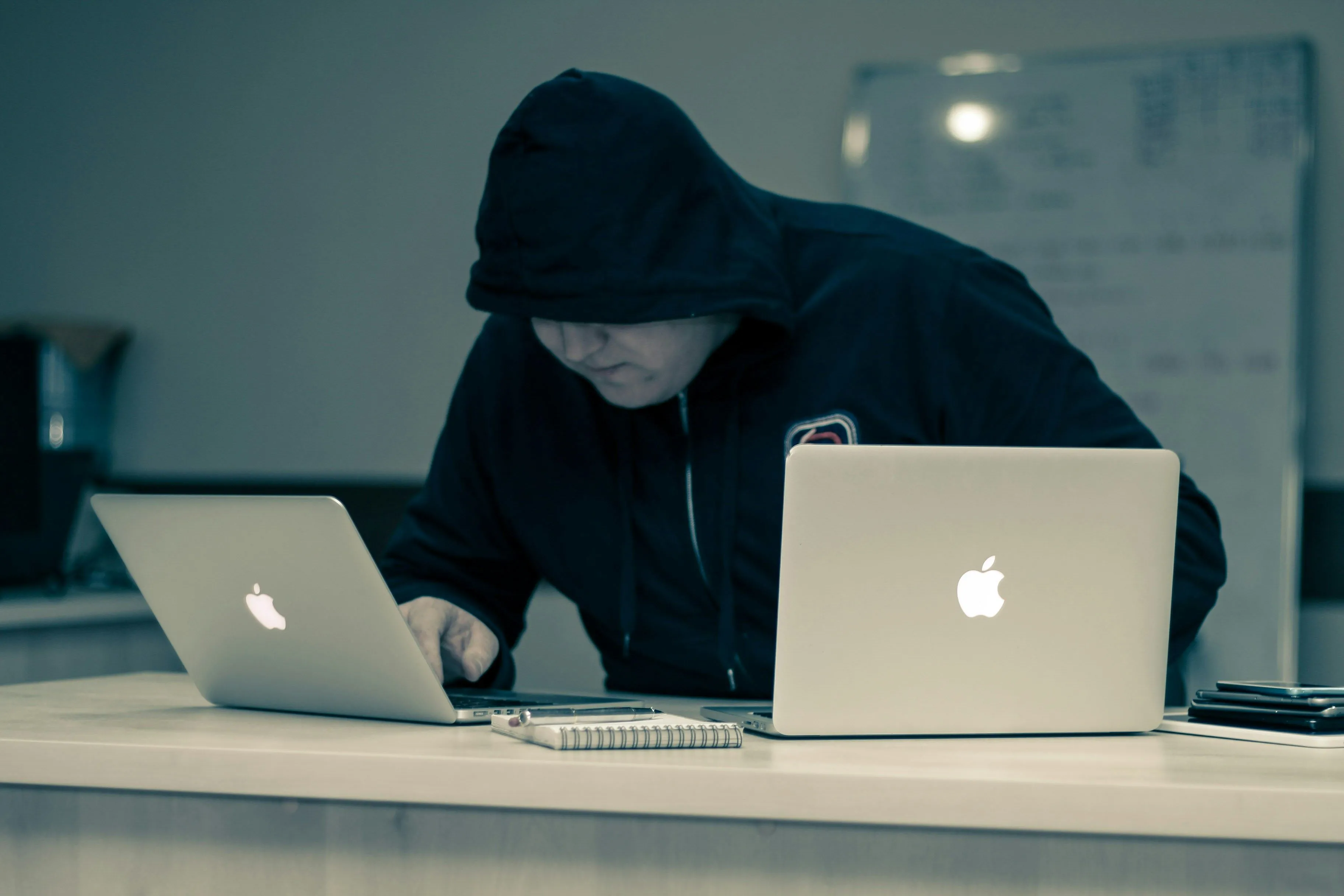 Tin tặc đang gõ máy tính xách tay Apple, tượng trưng cho mối đe dọa mạng